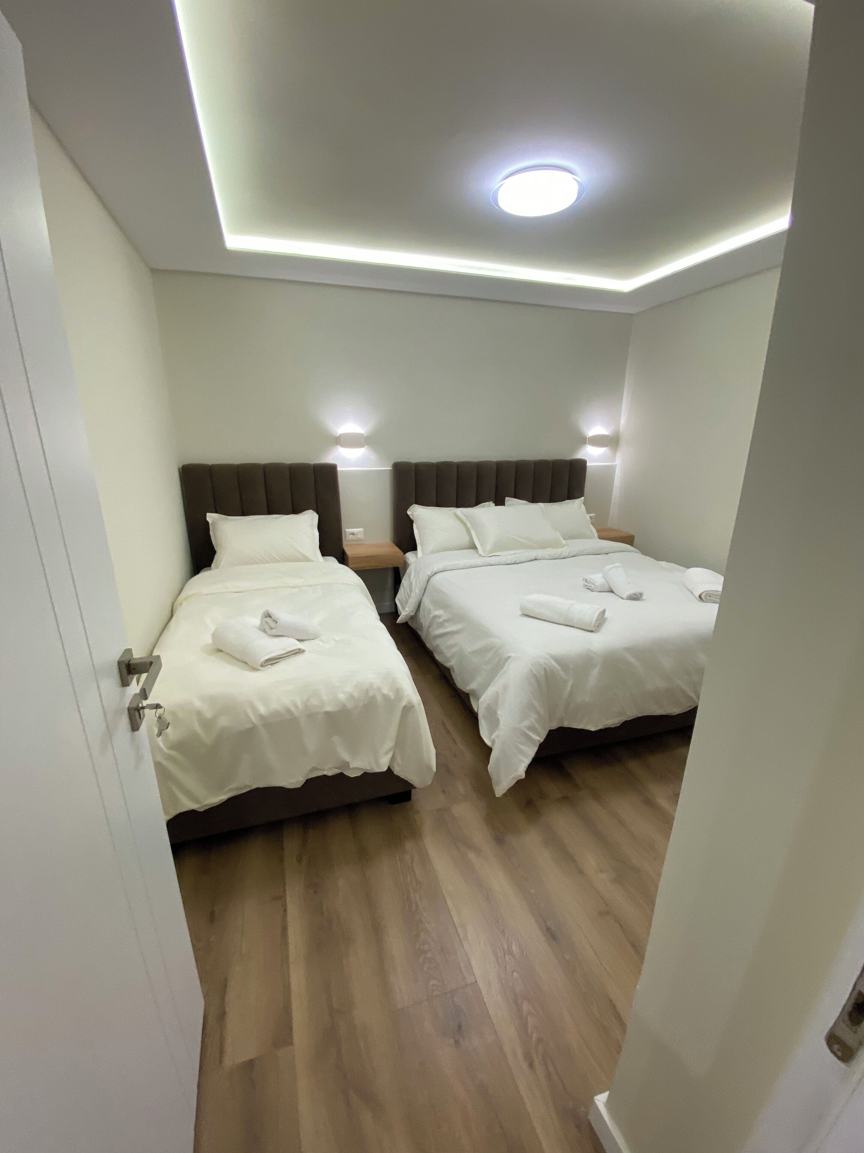 A hotel room with two beds, each with a headboard and bedside tables.