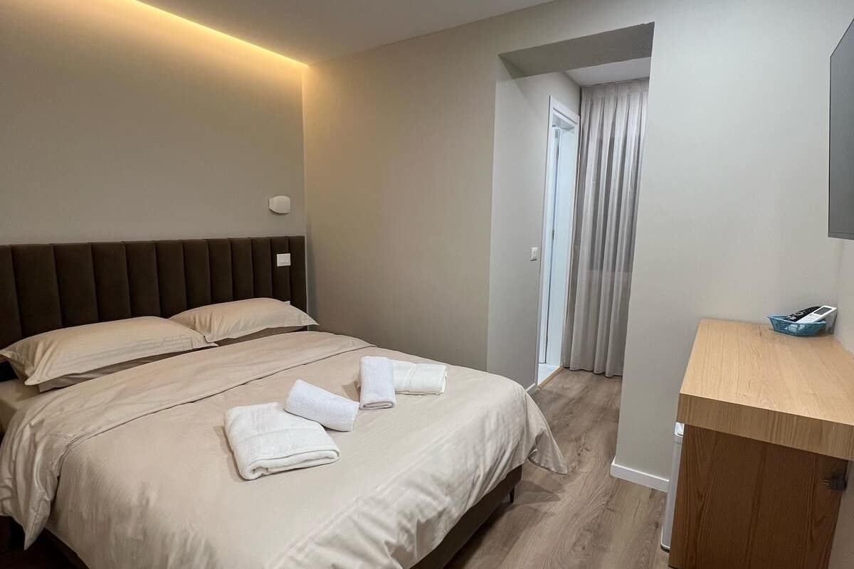 Een moderne hotelkamer met een groot bed, een houten bureau en een spiegel.