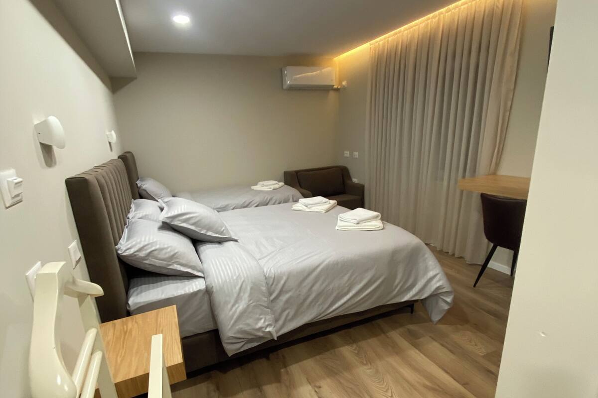 Een moderne slaapkamer met een bed, nachtkastjes, een bureau en een stoel.
