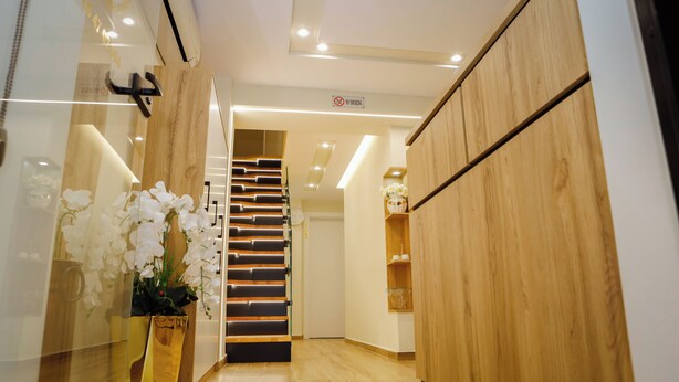 Un hall d’hôtel moderne avec un escalier en bois, un comptoir d’accueil et une orchidée en pot.