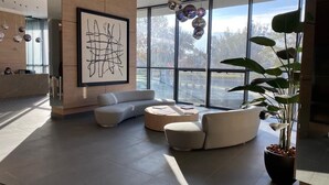 Un moderno vestíbulo con un sofá modular, una mesa de centro redonda y un cuadro abstracto de gran tamaño.