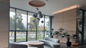 Un interior moderno con ventanas amplias, un sofá curvo, una mesita de centro redonda y una planta en maceta.