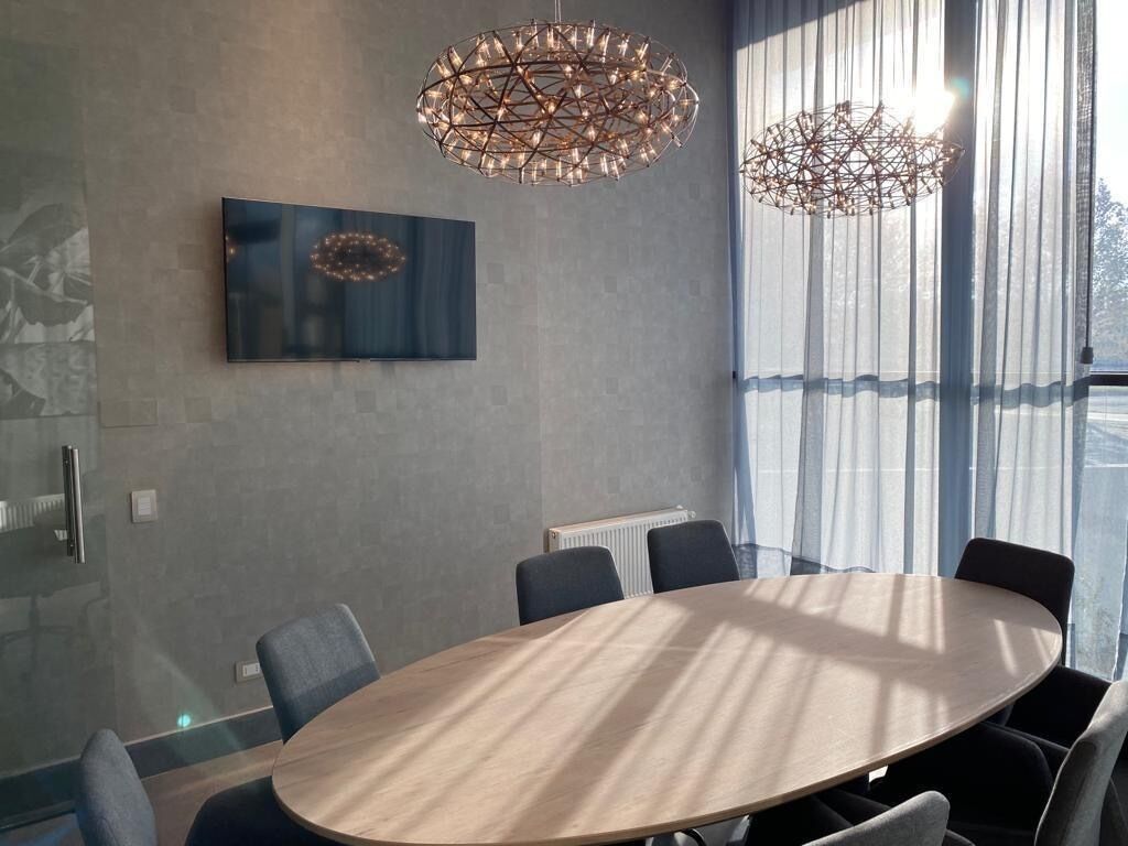 A modern conference room with a round table, chairs, and two hanging light fixtures.