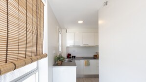 Eine moderne Küche mit weißen Schränken, einer Edelstahl-Spüle und einem Fenster mit Bambusrollos.
