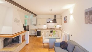 A modern kitchen with white cabinets, a dining table with chairs, a built-in fireplace, and a cityscape painting on the wall. - Volta Apartment by Rent all Como (Como)