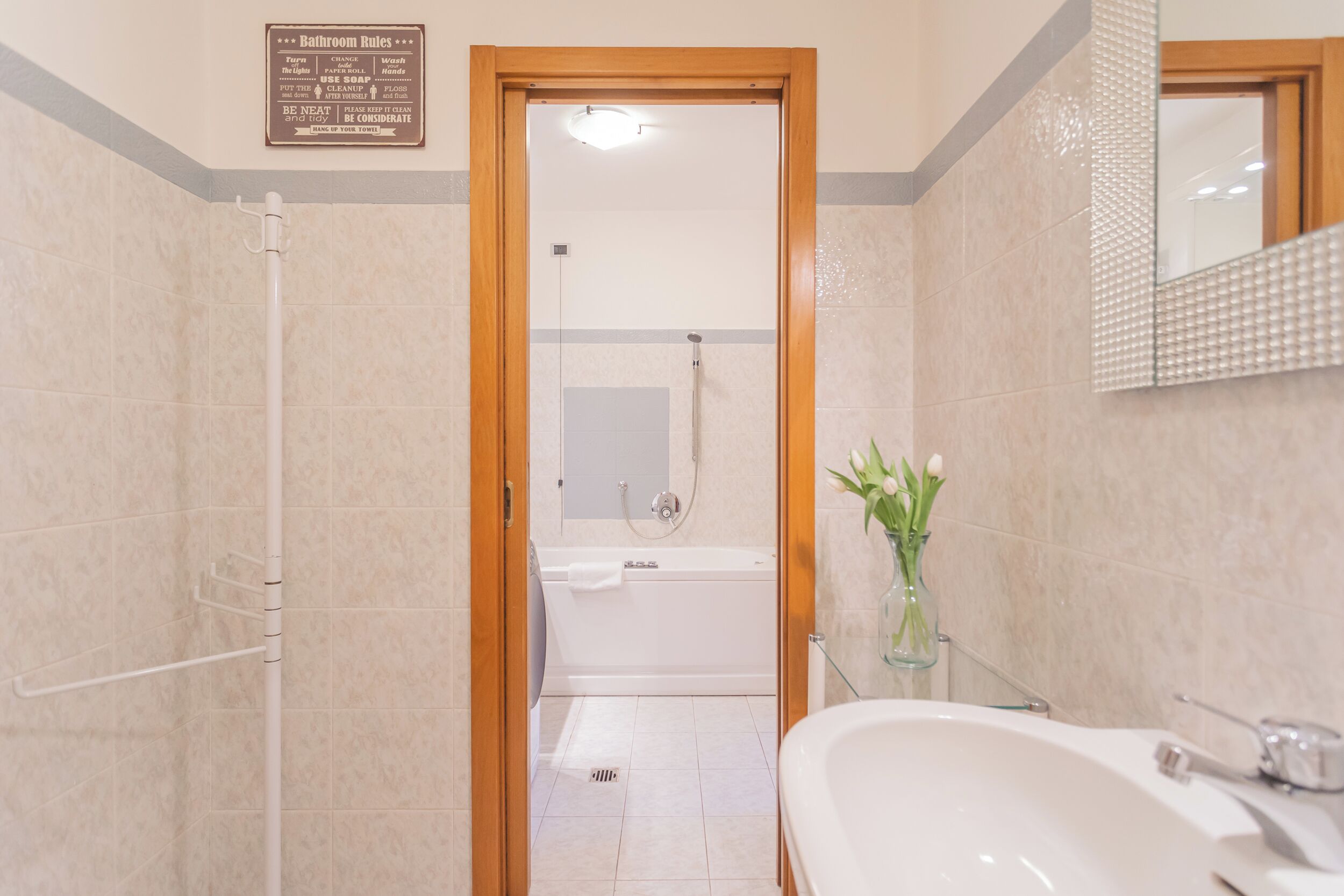 A bathroom with a shower, bathtub, and sink. There is a sign with bathroom rules on the wall.