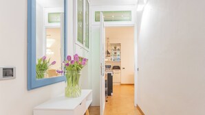 A hallway with a white console table, a vase with purple flowers, and a mirror. - Volta Apartment by Rent all Como (Como)