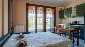 A bedroom with a bed, a table, and a view of the outside balcony. - Girasole Apartment - with air conditioning, garage and WiFi (Sirmione)