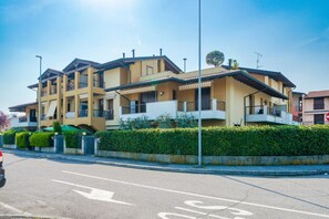 A multi-story residential building with balconies, a gated entrance, and a clear sky. - Girasole Apartment - with air conditioning, garage and WiFi (Sirmione)