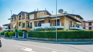 A multi-story residential building with balconies, a gated entrance, and a clear sky. - Girasole Apartment - with air conditioning, garage and WiFi (Sirmione)