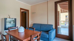 A dining area with a wooden table and chairs, a blue sofa, and a refrigerator labeled "Bistrot". - Girasole Apartment - with air conditioning, garage and WiFi (Sirmione)
