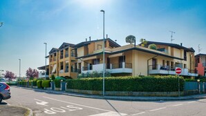 A multi-story residential building with balconies, a stop sign, and a clear sky. - Girasole Apartment - with air conditioning, garage and WiFi (Sirmione)