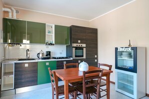A modern kitchen with a dining area, featuring a stove, oven, and a refrigerator.