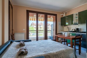 A bedroom with a bed, a table, and a view of the outside balcony. - Girasole Apartment - with air conditioning, garage and WiFi (Sirmione)