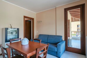 A dining area with a wooden table and chairs, a blue sofa, and a refrigerator labeled "Bistrot". - Girasole Apartment - with air conditioning, garage and WiFi (Sirmione)