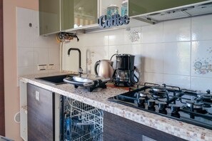 Cozinha equipada com fogão a gás, cafeteira e máquina de lavar louça.