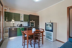 Uma cozinha compacta com uma mesa de jantar e cadeiras, forno embutido e geladeira.