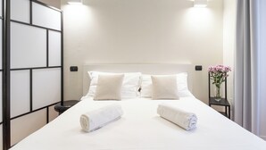 Una habitación de hotel con una cama grande, dos mesitas de noche y un florero con flores.