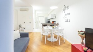 Una sala de estar moderna con un sofá gris, una mesa de comedor con sillas blancas, un mueble rojo para entretenimiento y una pared con una cita motivacional.