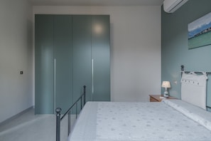Ein Schlafzimmer mit einem Bett, einem Nachttisch, einer Lampe, einem Kleiderschrank und einem Bild an der Wand.