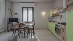 A compact kitchen with a dining area, a TV, and a window with curtains.