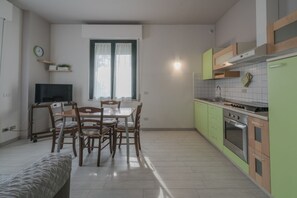 Een kleine keuken met een eethoek, een televisie en een raam met gordijnen.