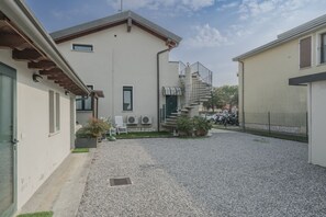 A residential building with a gravel driveway, a staircase leading to a second floor, and outdoor seating. - Villa Natalina - Two-Bedroom Apartment with Air Conditioning and Wi-Fi (Sirmione)