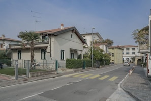 Eine Wohnstraße mit Häusern, einem Fußgängerüberweg und einem am Straßenrand geparkten Auto.