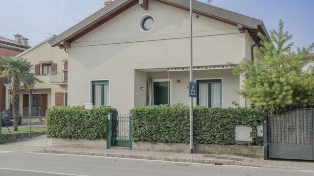 Un bâtiment d’un seul étage, doté d’un toit plat, d’une petite fenêtre ronde et d’une porte verte.