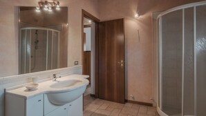 Une salle de bain avec un double lavabo, un miroir, une cabine de douche et une porte en bois.