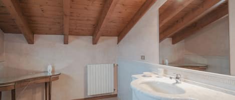 A bathroom with a wooden ceiling, a white sink, and a mirror.