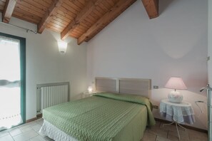 Une chambre à coucher avec un lit, une table de chevet, une lampe et une fenêtre.