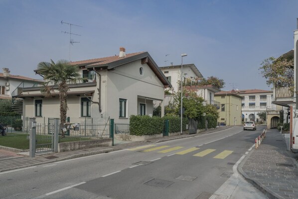 Une rue résidentielle bordée de maisons, avec un passage piéton et une voiture garée sur le bord.