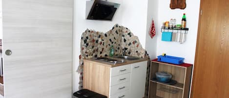 A compact kitchen with a microwave, sink, and storage shelves.