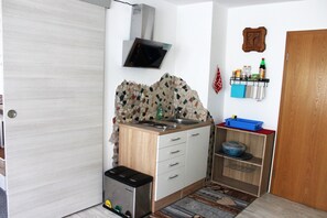 Une cuisine compacte équipée d’un four à micro-ondes, d’un évier et d’étagères de rangement.