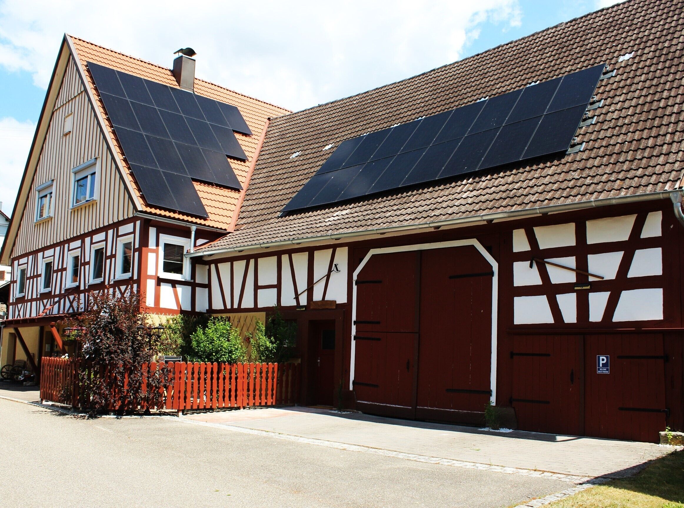 En traditionell byggnad med korsvirkesfasad, solpaneler på taket och en röd garageport.