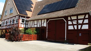 Un edificio tradicional con entramado de madera y paneles solares en el techo, con una puerta de garaje roja.