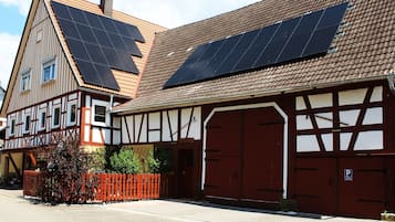 En traditionell byggnad med korsvirkesfasad, solpaneler på taket och en röd garageport.