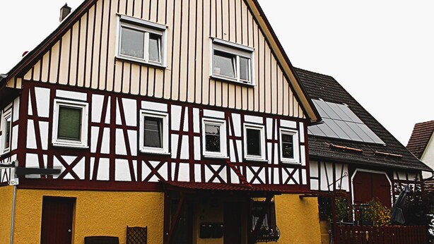 Una casa tradicional con entramado de madera, techo a dos aguas, puerta principal y un pequeño porche.