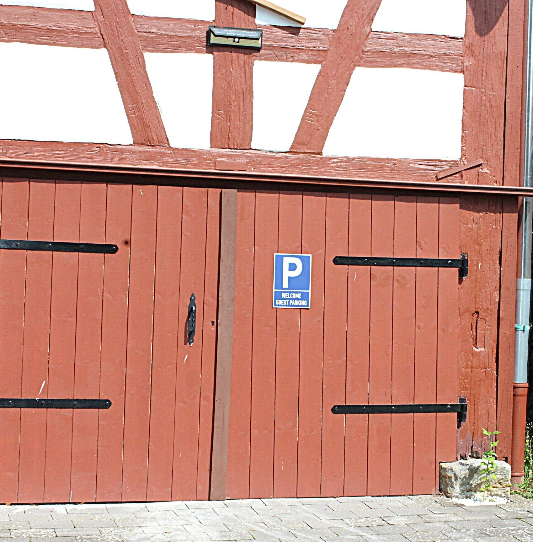 A red wooden gate with a blue 'P' sign indicating guest parking.