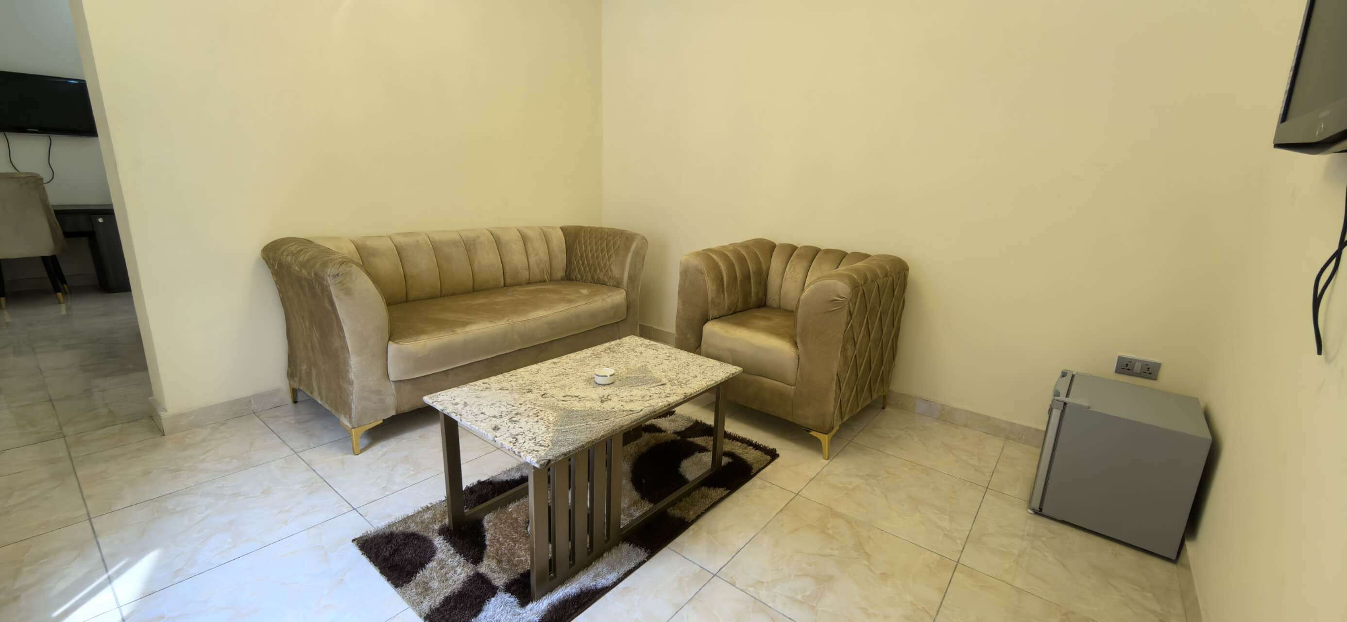 A living room with a beige sofa, a matching armchair, a coffee table, and a small cabinet.