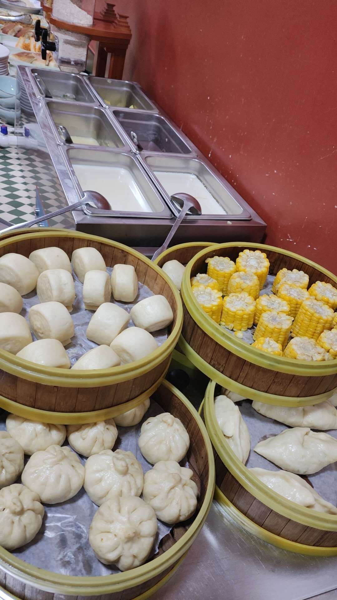 Un buffet proposant une variété de plats, notamment des raviolis et des épis de maïs.