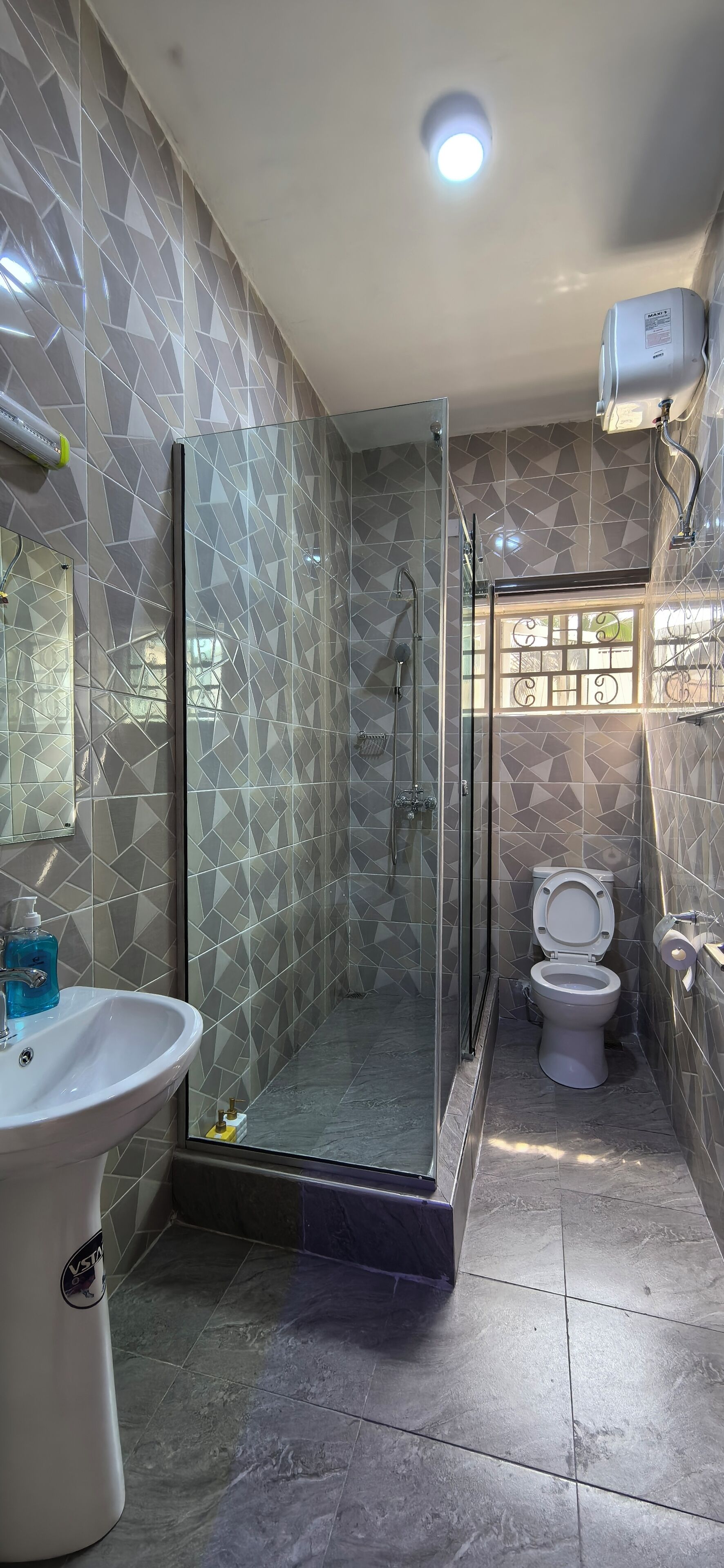 A bathroom with a glass-enclosed shower, a white sink, and a toilet.