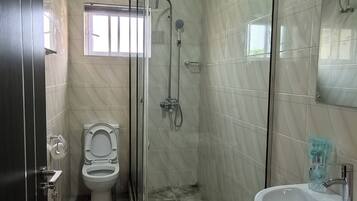 Un baño con ducha de vidrio, inodoro y lavamanos.