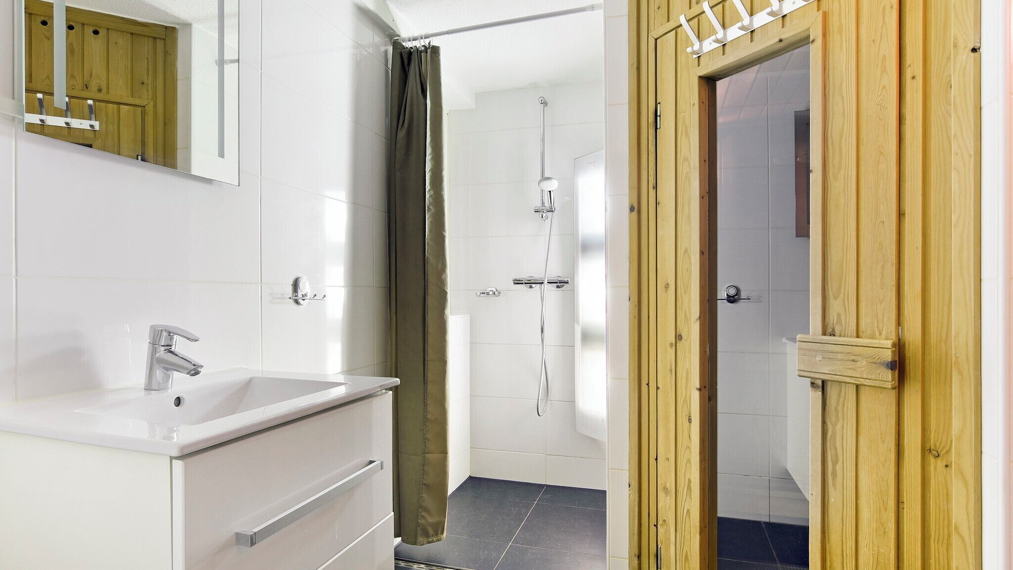 Une salle de bain avec un lavabo blanc, un miroir et un espace douche.