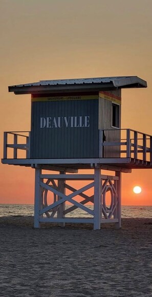A lifeguard station named 'DEAUVILLE' with a metal roof and a wooden deck.