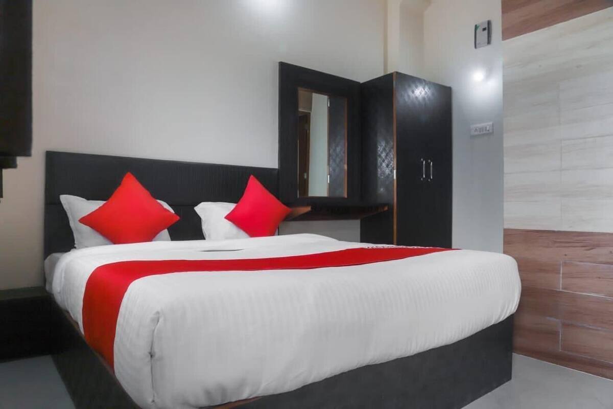 Habitació d'hotel amb un llit gran, un panell de capçaleri fosc i una paret de destaca decorada amb fusta.