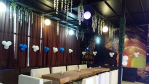 Ein Restaurant mit Sitzecken und Tischen, hängenden Pflanzen und Ballons.