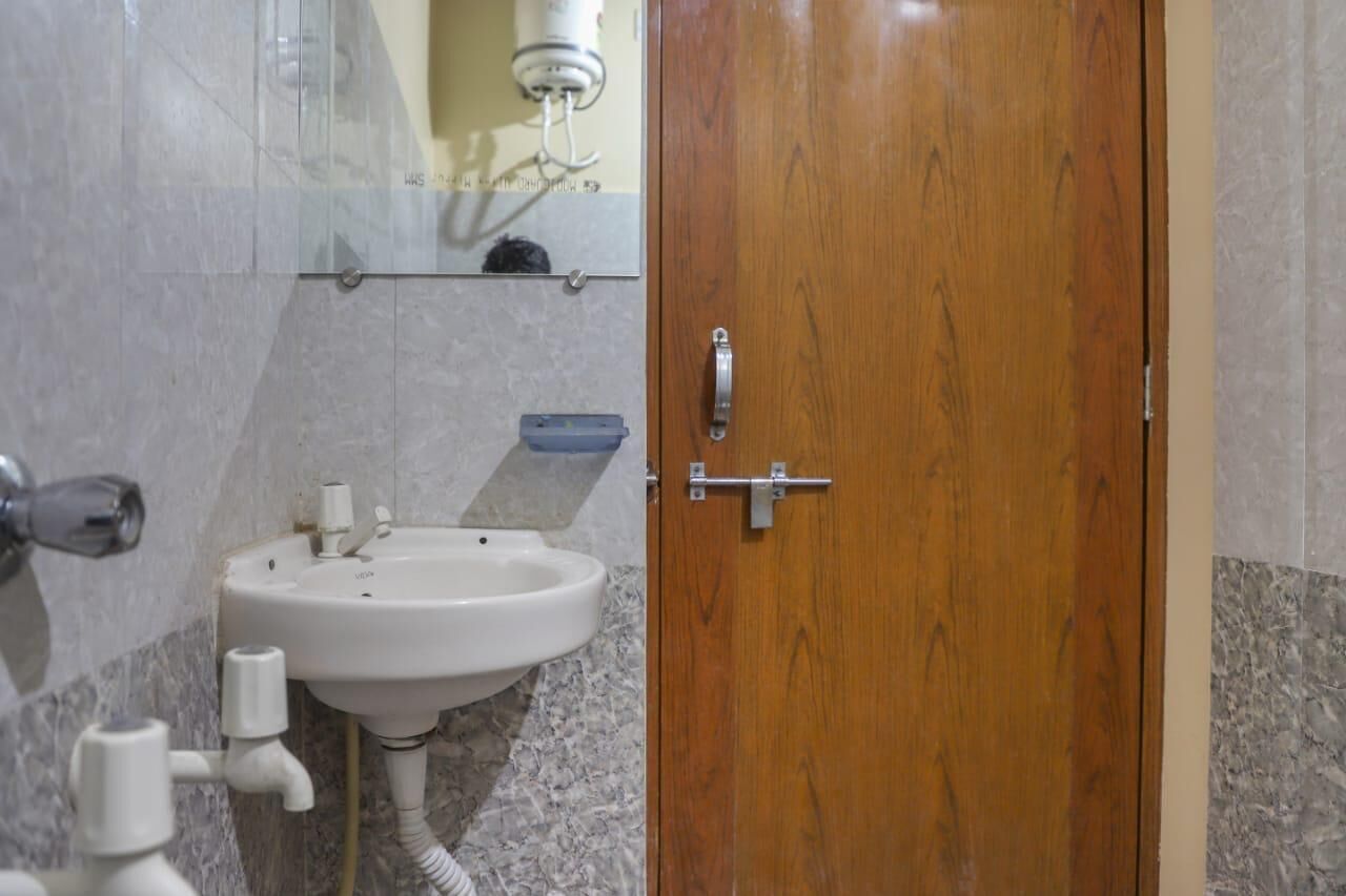 A bathroom with a wooden door, a white sink, and a mirror above it.