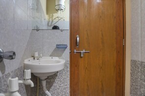 A bathroom with a wooden door, a white sink, and a mirror above it. - Shanti Heritage Resort By GRB (Guna)